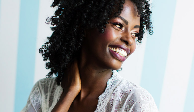 Mulher negra sorrindo com a mão no pescoço sexualidade