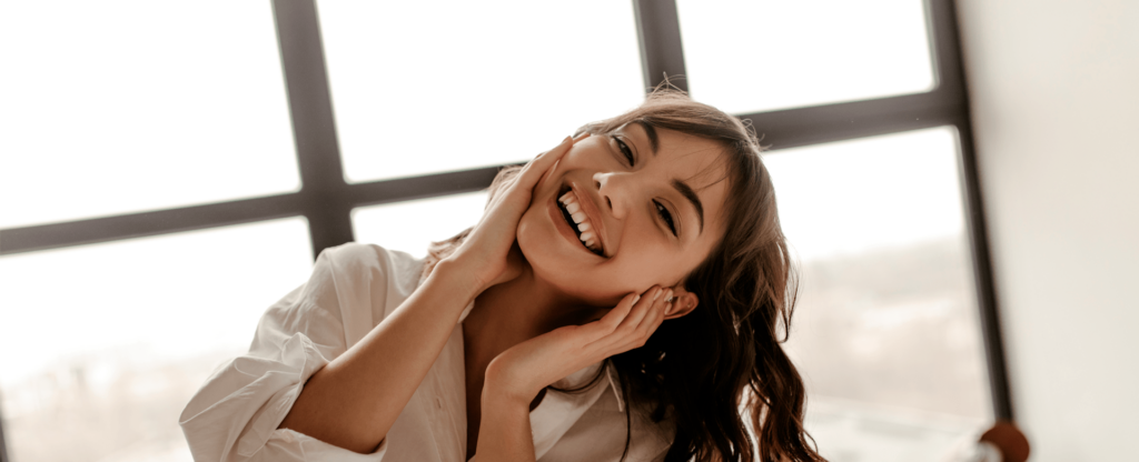 Mulher sorrindo para uma fotografia após praticar os cuidados com a pele.
