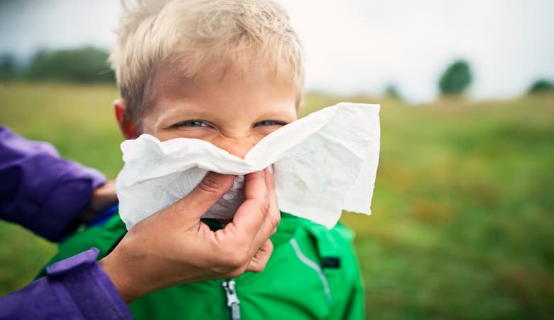Mãe realizando a limpeza nasal externa em seu filho com um lenço umidecido. 