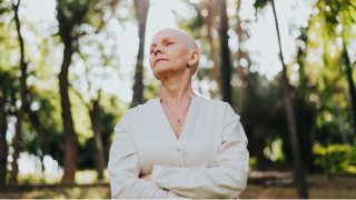 Mulher com câncer de mama pensativa em meio a natureza.