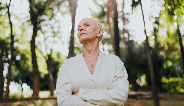 Mulher com câncer de mama pensativa em meio a natureza.