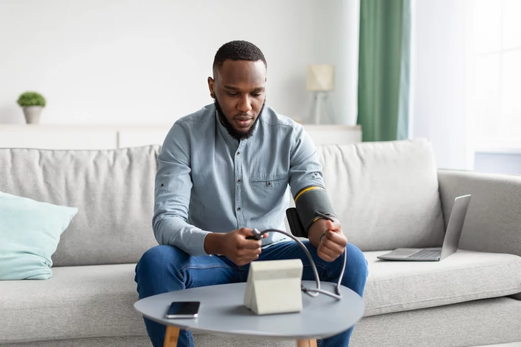 homem aferindo sua pressao sentado no sofa