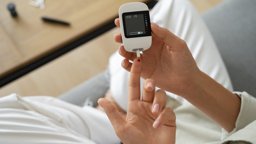 mãos de uma mulher com diabetes utilizando um aparelho para checar seu nível de glicose
