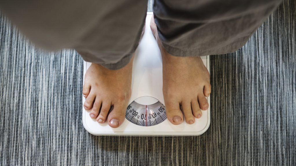 Pés de uma pessoa que está em pé sobre uma balança se pesando
